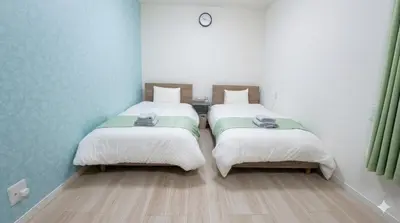 two beds in a room with white walls and wooden floors at APRO STAY\u7fbd\u7530 garden7 201\u53f7\u5ba4 in Tokyo