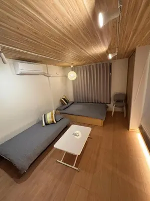a small room with two beds and a table at Wing Stay in Tokyo