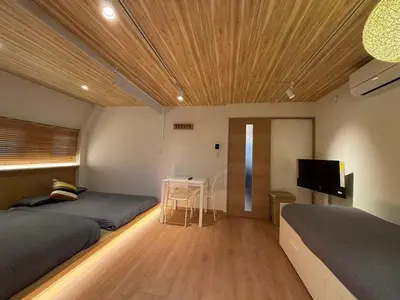 a bedroom with two beds and a desk and a television at Wing Stay in Tokyo