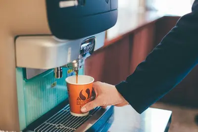 a person pouring a coffee into a coffee machine at Kuretake-Inn Tokyo Funabori in Tokyo