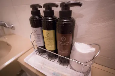 a rack with three bottles of hair products on a sink at Kuretake-Inn Tokyo Funabori in Tokyo