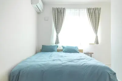 a bedroom with a bed with blue sheets and a window at Featured Japanese Culture Hut Experience Tokyo's Local Life in a Two-Story Detached B&B in Tokyo