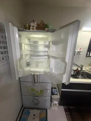 an empty refrigerator with its door open in a kitchen at sakura\u306e\u5bb6 in Tokyo