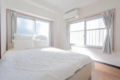 a white bedroom with a large bed with windows at \u65b0\u5bbf\u99c5\u30a8\u30ea\u30a2\u5f92\u6b69\u570f \u4ea4\u901a\u81f3\u4fbf \u89b3\u5149 \u30b7\u30e7\u30c3\u30d4\u30f3\u30b0 \u30b0\u30eb\u30e1\u306b\u6700\u9069\u306a\u5317\u65b0\u5bbf\u30b9\u30c6\u30a4 in Tokyo