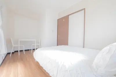 a white bedroom with a white bed and a table at \u65b0\u5bbf\u99c5\u30a8\u30ea\u30a2\u5f92\u6b69\u570f \u4ea4\u901a\u81f3\u4fbf \u89b3\u5149 \u30b7\u30e7\u30c3\u30d4\u30f3\u30b0 \u30b0\u30eb\u30e1\u306b\u6700\u9069\u306a\u5317\u65b0\u5bbf\u30b9\u30c6\u30a4 in Tokyo