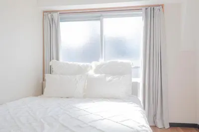 a bed with white pillows in front of a window at \u65b0\u5bbf\u99c5\u30a8\u30ea\u30a2\u5f92\u6b69\u570f \u4ea4\u901a\u81f3\u4fbf \u89b3\u5149 \u30b7\u30e7\u30c3\u30d4\u30f3\u30b0 \u30b0\u30eb\u30e1\u306b\u6700\u9069\u306a\u5317\u65b0\u5bbf\u30b9\u30c6\u30a4 in Tokyo