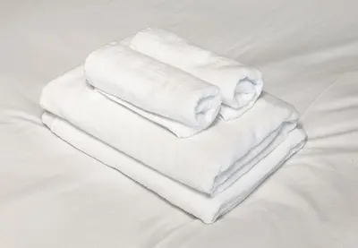 three towels are stacked on top of a bed at Marble TOKYO Base Tabata 202 in Tokyo