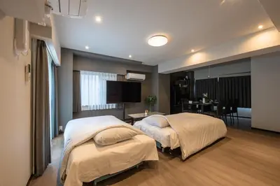 a bedroom with two beds and a table and a television at Ebisu City Stay 5F - \u6075\u6bd4\u5bff \u30b7\u30c6\u30a3\u30b9\u30c6\u30a4 5F in Tokyo