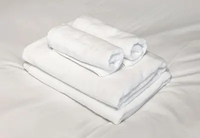 three towels are stacked on top of a bed at Marble TOKYO Base Tabata 301 in Tokyo