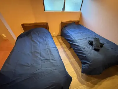 two beds in a room with a blue sleeping bag at BEDandBAR MIDUKI \u30db\u30b9\u30c6\u30eb in Tokyo