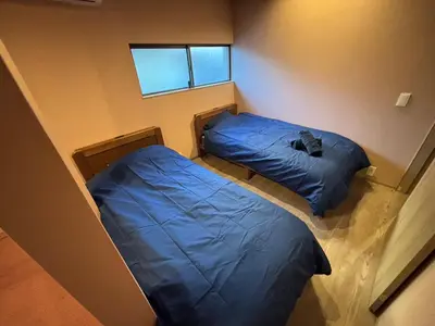 two beds in a small room with a window at BEDandBAR MIDUKI \u30db\u30b9\u30c6\u30eb in Tokyo