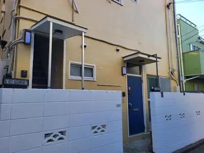 a building with a fence and a blue door at 1F TINY Central Apartment 7 Minutes from Shinjuku in Tokyo