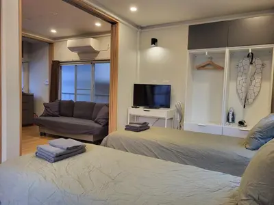 a bedroom with two beds and a couch and a television at 1F TINY Central Apartment 7 Minutes from Shinjuku in Tokyo