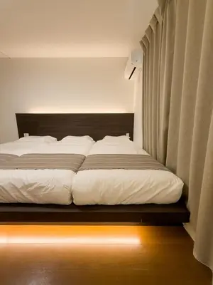 a bedroom with a large bed with white sheets at ISSHUKU NOMA\u6c60\u888bII 203 - Quad Room in Tokyo