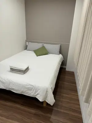 a white bed with a green pillow on top of it at C&H hotel2F in Tokyo