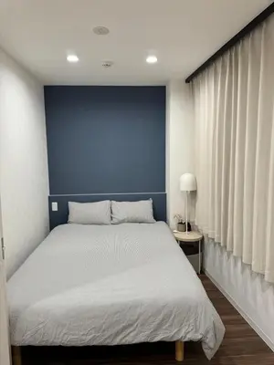 a bedroom with a bed with a blue wall at C&H hotel1F in Tokyo