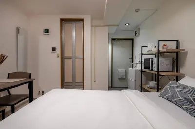 a bedroom with a large white bed and a desk at CraftFlat Numabukuro 303, uphill residence in Tokyo
