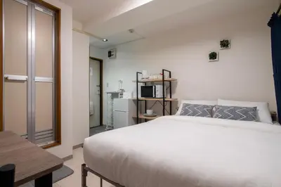 a bedroom with a large white bed and a microwave at CraftFlat Numabukuro 303, uphill residence in Tokyo