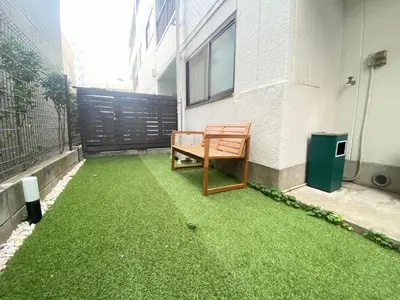 a bench sitting on the grass outside of a building at F-City \u4e2d\u845b\u897f I in Tokyo