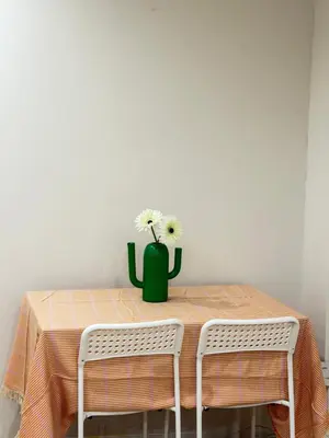a table with a green vase with flowers on it at C&H 5丁目B1ｆ in Tokyo