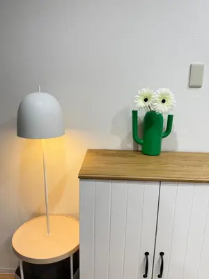 a table with a lamp and two white flowers in a vase at C&H 5丁目B1ｆ in Tokyo
