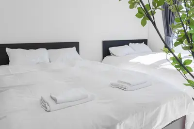 a white bed with two folded towels on it at \u30a8\u30c9\u30e2\u30c0\u30f3\u30b9\u30c6\u30a4 Edo Modern Stay 02 in Tokyo