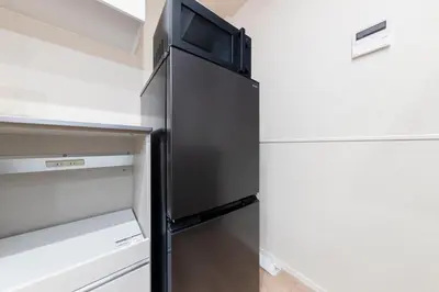 a black refrigerator in a kitchen with white cabinets at \u30d9\u30eb\u30d3\u30fc\u4eac\u5cf6 Belle Vie Kyoujima in Tokyo