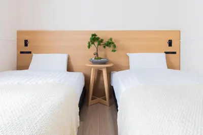 two beds with white sheets and a plant on a table at \u30d9\u30eb\u30d3\u30fc\u4eac\u5cf6 Belle Vie Kyoujima in Tokyo