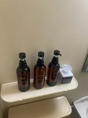 three bottles of honey sitting on a shelf above a toilet at \u30d5\u30a1\u30fc\u30b9\u30c8\u30cf\u30a4\u30c4401 in Tokyo