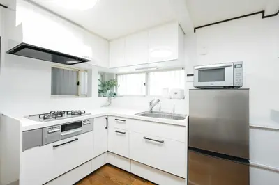 a kitchen with white cabinets and a stainless steel refrigerator at Magome tokyo stay in Tokyo