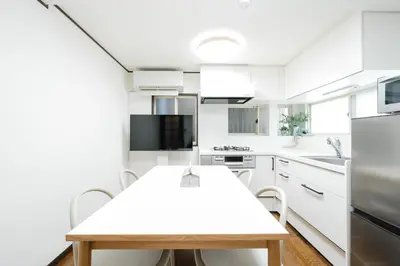 a kitchen with white cabinets and a wooden table at Magome tokyo stay in Tokyo