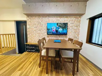 a dining room table with chairs and a tv on a brick wall at NYCottageAnnex2\u5ba41\u30ea\u30d3\u30f3\u30b01\u30b7\u30e3\u30ef\u30fc1\u30c8\u30a4\u30ec in Tokyo