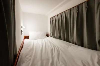 a bedroom with a white bed with a curtain at Wa Hostel in Tokyo