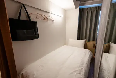 a small room with a bed and a bag on the wall at Wa Hostel in Tokyo