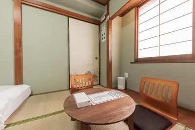 a room with a table and two chairs and a bed at Tourist Hotel New Aoki \u89b3\u5149\u30db\u30c6\u30eb \u30cb\u30e5\u30fc\u9752\u6728 in Tokyo