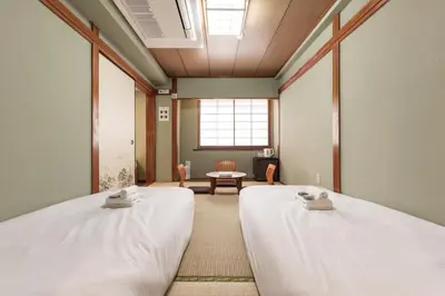 a room with two beds and a table in it at Tourist Hotel New Aoki \u89b3\u5149\u30db\u30c6\u30eb \u30cb\u30e5\u30fc\u9752\u6728 in Tokyo