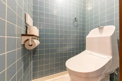 a blue tiled bathroom with a toilet in it at Tourist Hotel New Aoki \u89b3\u5149\u30db\u30c6\u30eb \u30cb\u30e5\u30fc\u9752\u6728 in Tokyo