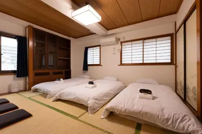 two beds in a room with wooden ceilings and windows at Tourist Hotel New Aoki \u89b3\u5149\u30db\u30c6\u30eb \u30cb\u30e5\u30fc\u9752\u6728 in Tokyo