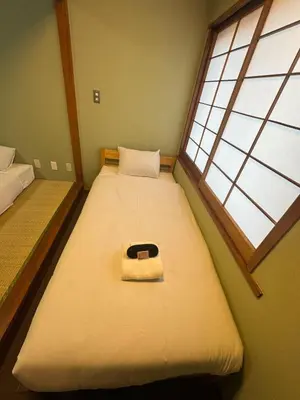 two beds in a room with a window at Tourist Hotel New Aoki \u89b3\u5149\u30db\u30c6\u30eb \u30cb\u30e5\u30fc\u9752\u6728 in Tokyo