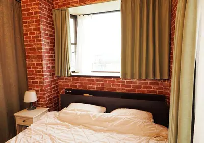 a brick walled bedroom with a bed and a window at 301 Koiwa Grand House in Tokyo