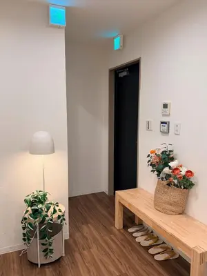 a hallway with a bench and two potted plants at C&H hotel3F in Tokyo