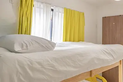 a bed in a room with a yellow curtain at Otsuka 7 mins one stop to Ikebukuro mansion with garden in Tokyo