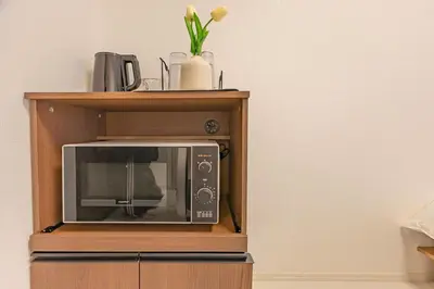 a microwave oven on a wooden stand with flowers at Otsuka 7 mins one stop to Ikebukuro mansion with garden in Tokyo