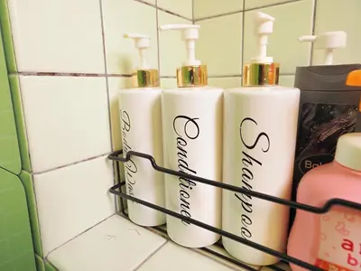 a group of three white shampoo bottles in a rack in a bathroom at Koiwa Guesthouse Tokyo in Tokyo