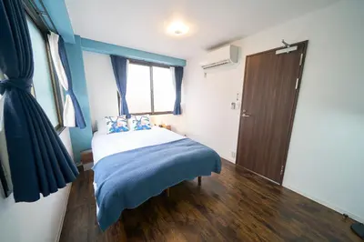 a bedroom with a bed with blue walls and a window at Clavis Asakusa Skytree in Tokyo