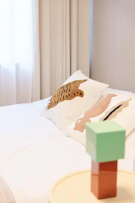 a bed with white sheets and pillows with a green box at TORA HOTEL Kamata in Tokyo