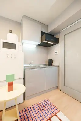 a kitchen with white cabinets and a table and a counter at TORA HOTEL Kamata in Tokyo