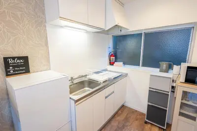 a small kitchen with white cabinets and a sink at Hale Akasaka - The House in Tokyo