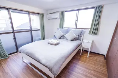 a small bedroom with a bed with windows at Charming Guesthouse in the Heart of Okubo \u4e36Steps to Metro and Convenient Travel! SoW in Tokyo