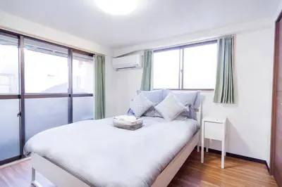 a bedroom with a white bed with windows at Charming Guesthouse in the Heart of Okubo \u4e36Steps to Metro and Convenient Travel! SoW in Tokyo